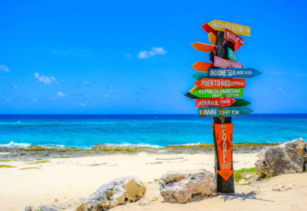 Iconic Cozumel Mexico beach signpost with turquoise Caribbean water and white sand for cruise passenger shore excursion planning